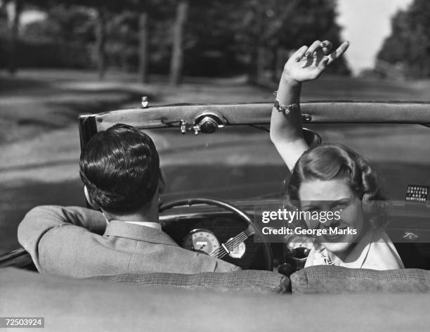 1950s: Couple driving in convertible.