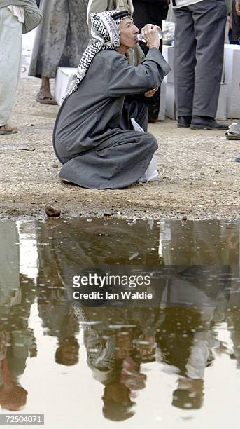 An Iraqi man takes a drink of fresh water as hundreds of Iraqis gather at the back of Red Crescent Society trucks carrying humanitarian aid in the...
