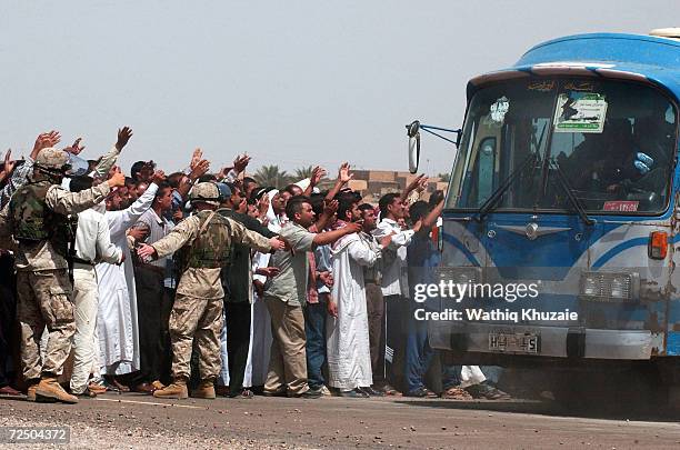 Bus load of freed Iraqi prisoners passes a group of waiting relatives after being released from Abu Ghraib prison May 21, 2004 outside of Baghdad,...