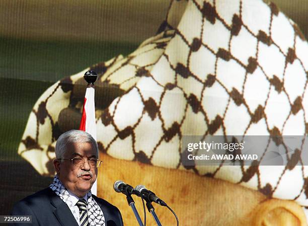 Palestinian President Mahmud Abbas speaks in front of a giant portrait of Palestinian patriarch Yasser Arafat wearing his trademark chequered...