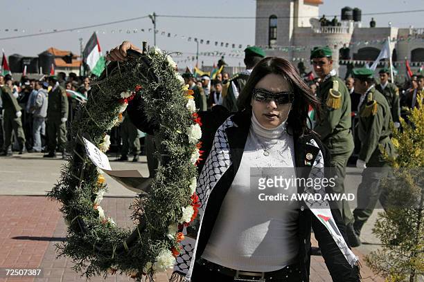 Palestinian woman carries a wreath during cermeonies commemorating the second anniversary of Yasser Arafat's death, 11 November 2006, in the West...