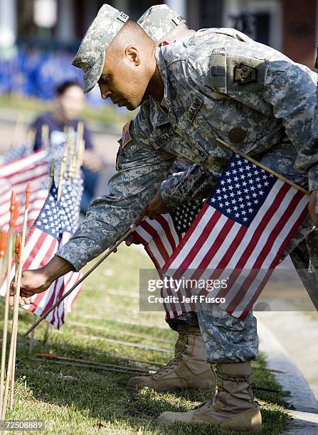 Members of the U.S. Armed Forces place flags at the Iraq War Flag Memorial during a Veterans Day ceremony at the Prospect Hill Cemetery November 11,...