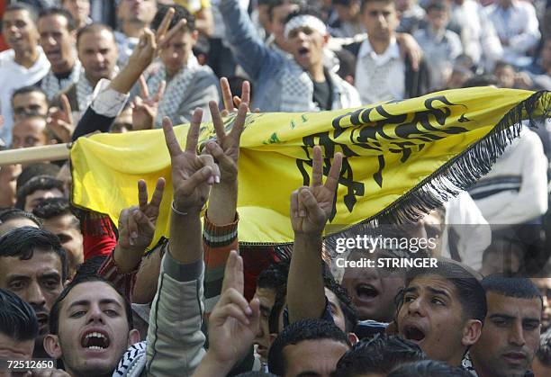 Palestinians supporters of the Fatah party show the V-sign for victory during a rally marking the second anniversary of the death of Palestinian...