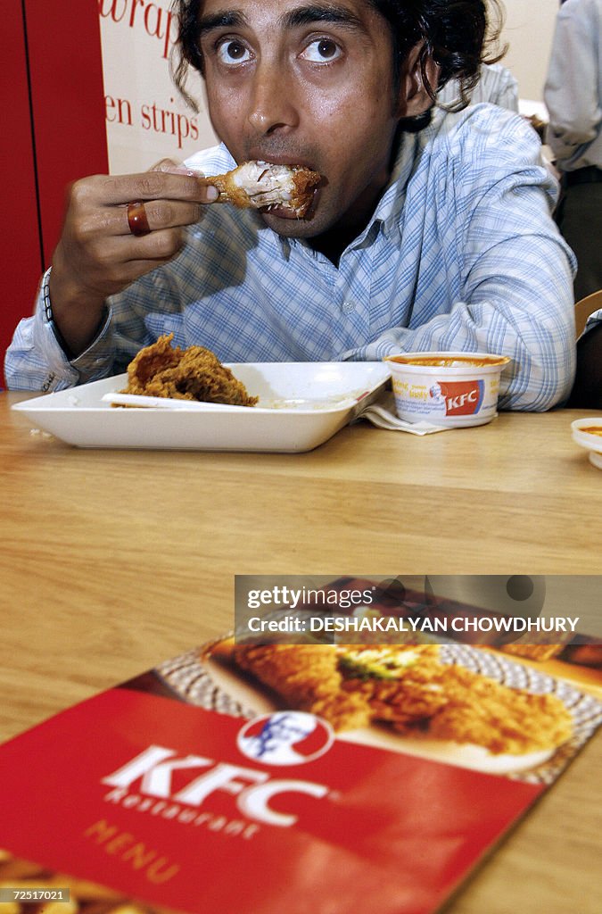 An Indian customer tastes a chicken prep