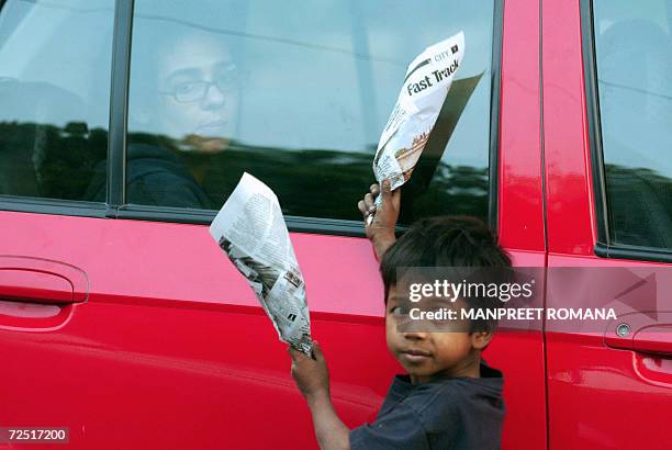 An Indian streetchild sells flowers wraped in newspaper sheets at a traffic light in New Delhi, 13 November 2006, on the eve of Children's Day....