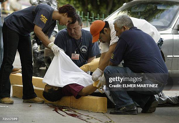 Tegucigalpa, HONDURAS: Empleados del Ministerio Publico de Honduras trabajan en el cuerpo de un guardia de seguridad tras ser abatido por...