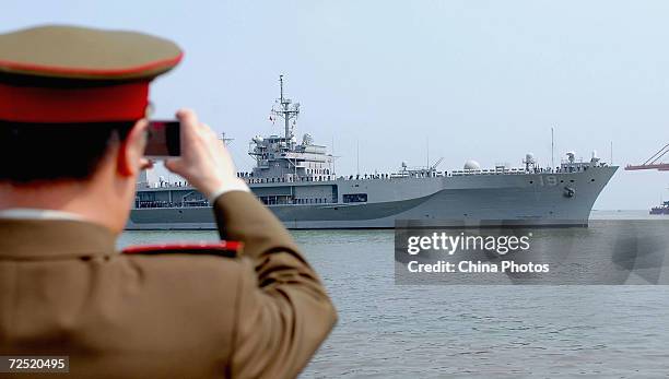 Chinese military officer takes pictures of the command ship Blue Ridge of the Seventh Fleet of the U.S. Navy after it arrived at a port on March 28,...