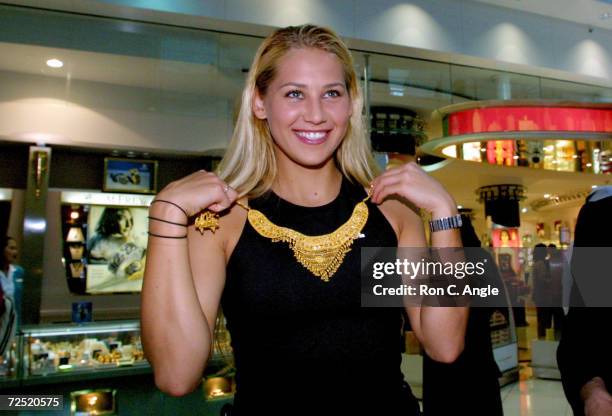 Russian tennis player Anna Kournikova tries on a solid gold necklace at the duty free shops at Dubai Airport February 17, 2002 in the United Arab...