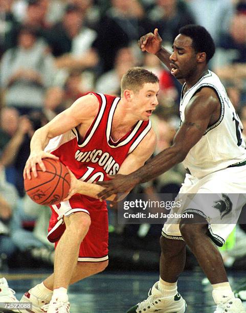 Jon Bryant of Wisconsin tries to dribble around Mateen Cleaves of Michigan State during the semifinal round of the NCAA Final Four at the RCA Dome in...