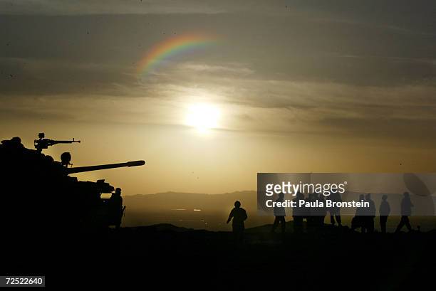 Afghan soldiers stand on top of a tank at sunset in the Shah-e-Kot mountain range, where they are stationed after returning from the front lines,...