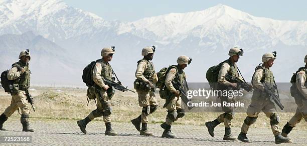 Army 10th Mountain Division soldiers walk across the tarmac as they prepare to enter a Chinook helicopter March 13, 2002 at the Bagram Air Base near...