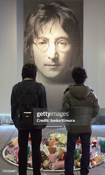 Two Japanese fans look at tributes laid in front of a giant photograph of John Lennon from at the John Lennon Museum on December 8, 2004 in Saitama,...