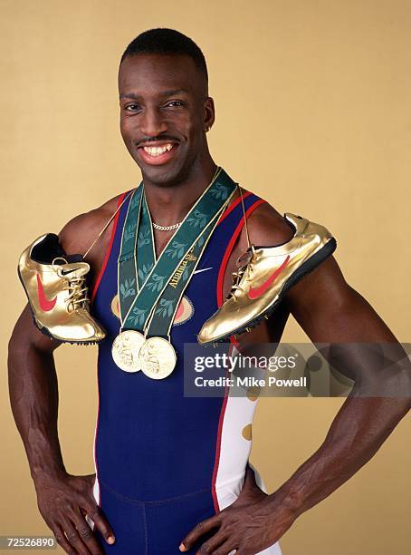 Sprinter Michael Johnson poses for a studio portrait with his two Olympic gold medals and his golden running shoes. Johnson became the first man to...