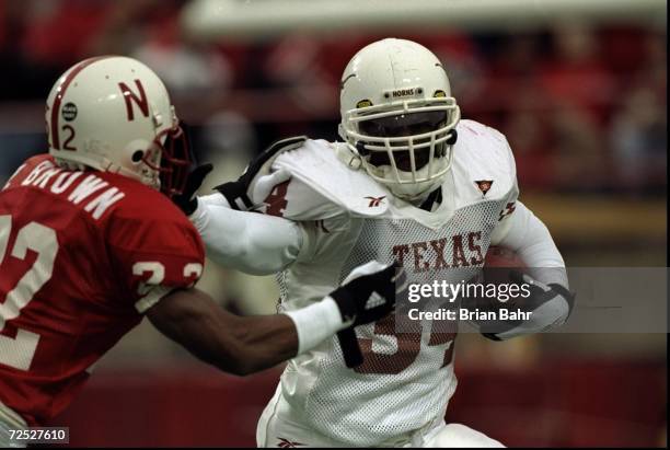 Ricky Williams of the Texas Longhorns grips the ball as he pushes Ralph Brown of the Nebraska Cornhuskers at Memorial Stadium in Lincoln, Nebraska....