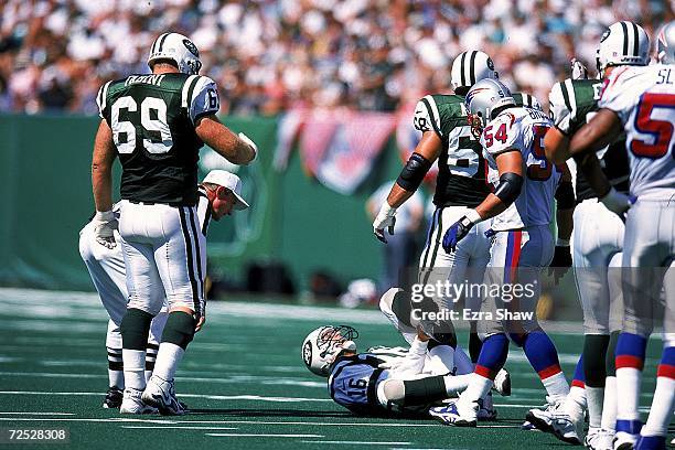 Vinny Testaverde of the New York Jets falls as he grabs his leg in pain during a game against the New England Patriots at the Giants Stadium in East...