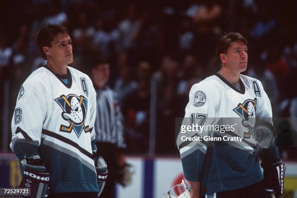 Forward Jari Kurri of the Anaheim Mighty Ducks along with teammate Teemu Selanne stand in attention as the National Anthem is played before before...