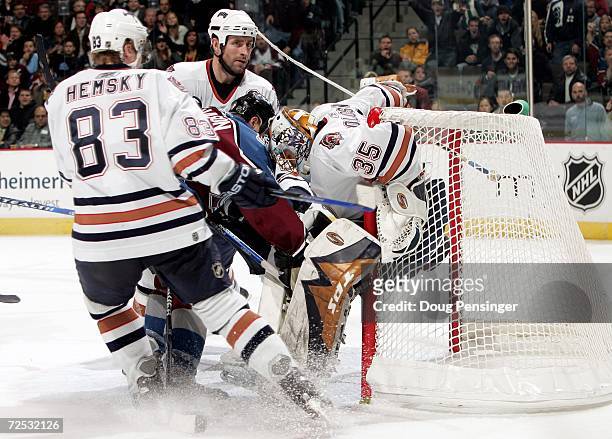 Goaltender Dwayne Roloson of the Edmonton Oilers collects the puck for a save as Tyler Arnason of the Colorado Avalanche pressures the goal while...