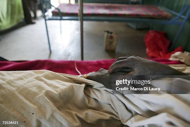 Relative holds hands with a Chadian villager as he recovers in his hospital bed from a gun shot wound, suffered in the recent fighting between ethnic...