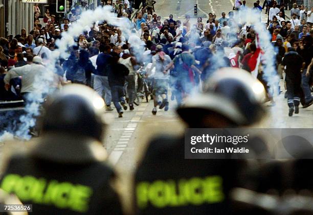 Swiss riot police in foreground fire tear gas at anti-G8 protesters June 1, 2003 in Geneva, Switzerland. After thousands of protesters rallied...