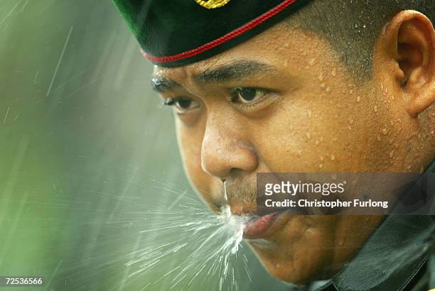 Soldier of the Brunei Army blows away rain streaming down his face during the torrential downpour over the royal procession of Bruneian Crown Prince...