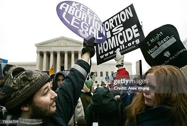 Pro-life activist Jessica Meunier of Fitchburg, MA, and pro-abortion activist Luqman Clark of Arlington, VA hold up signs as they protest outside...
