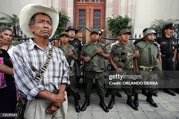 Soldados del Ejercito de Guatemala custodian la sede del Ejecutivo, mientras un hombre de la tercera edad participa en una marcha para exigir a los...