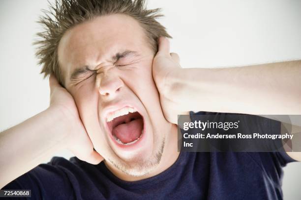 close up of man yelling and covering ears - hands covering ears stock-fotos und bilder