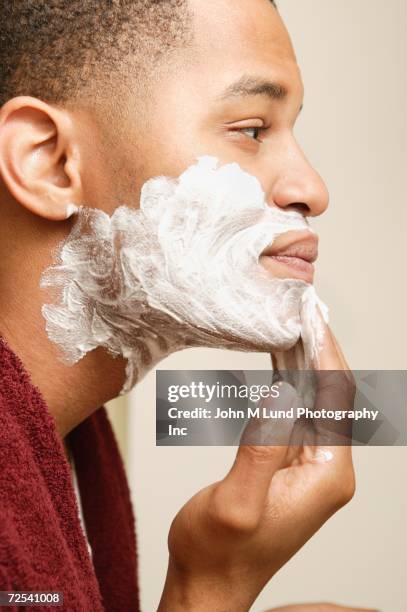 african man applying shaving cream to face - creme de barbear - fotografias e filmes do acervo