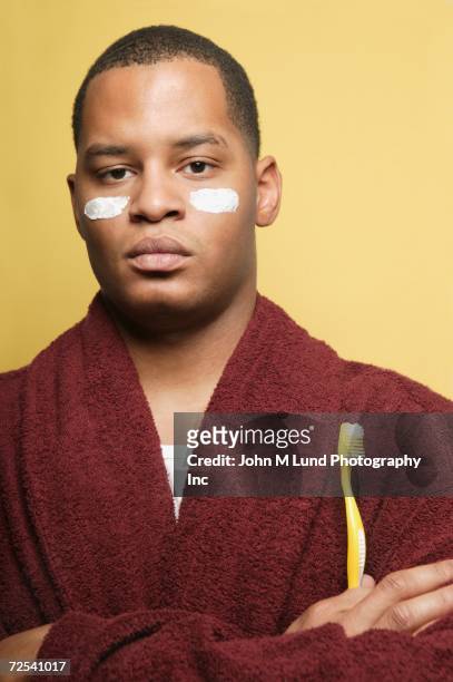 african man in bathrobe with toothbrush and white stripes on cheeks - hombre crema facial fotografías e imágenes de stock
