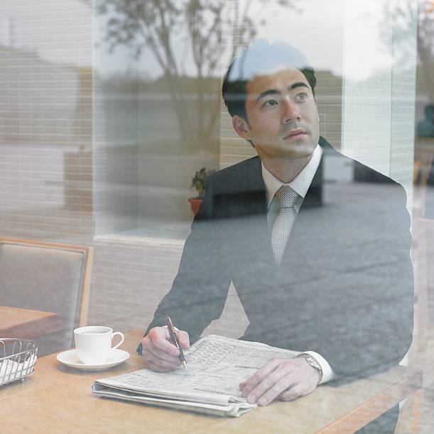 Asian businessman with paperwork looking out window