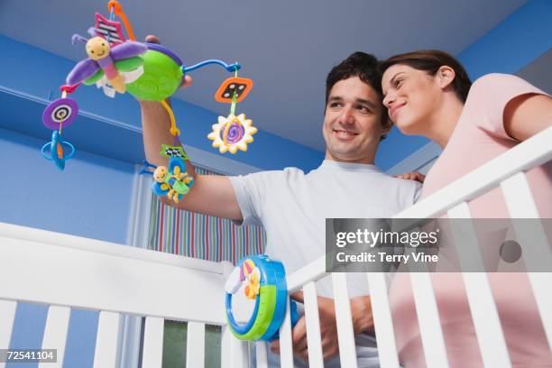 pregnant hispanic couple holding mobile over crib - baby mobile stock pictures, royalty-free photos & images