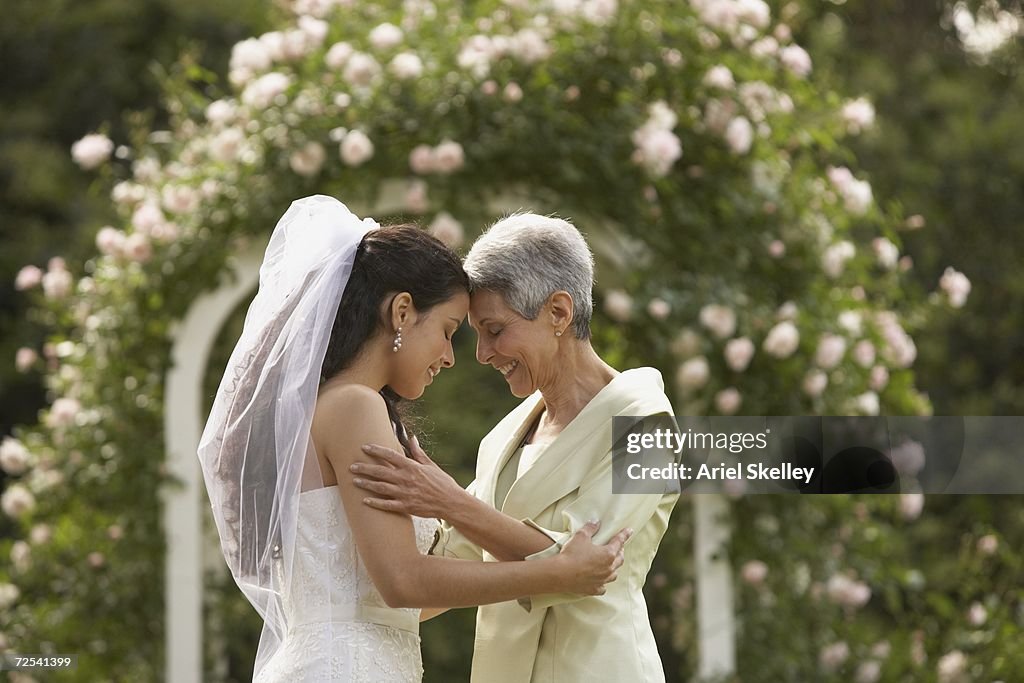 Hispanic bride and mother touching foreheads
