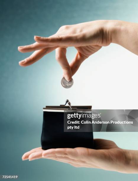 woman's hand dropping coin into change purse - gierig stockfoto's en -beelden