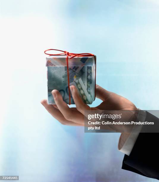 businessman's hand holding gift box made of euros - dangling a carrot stock-fotos und bilder