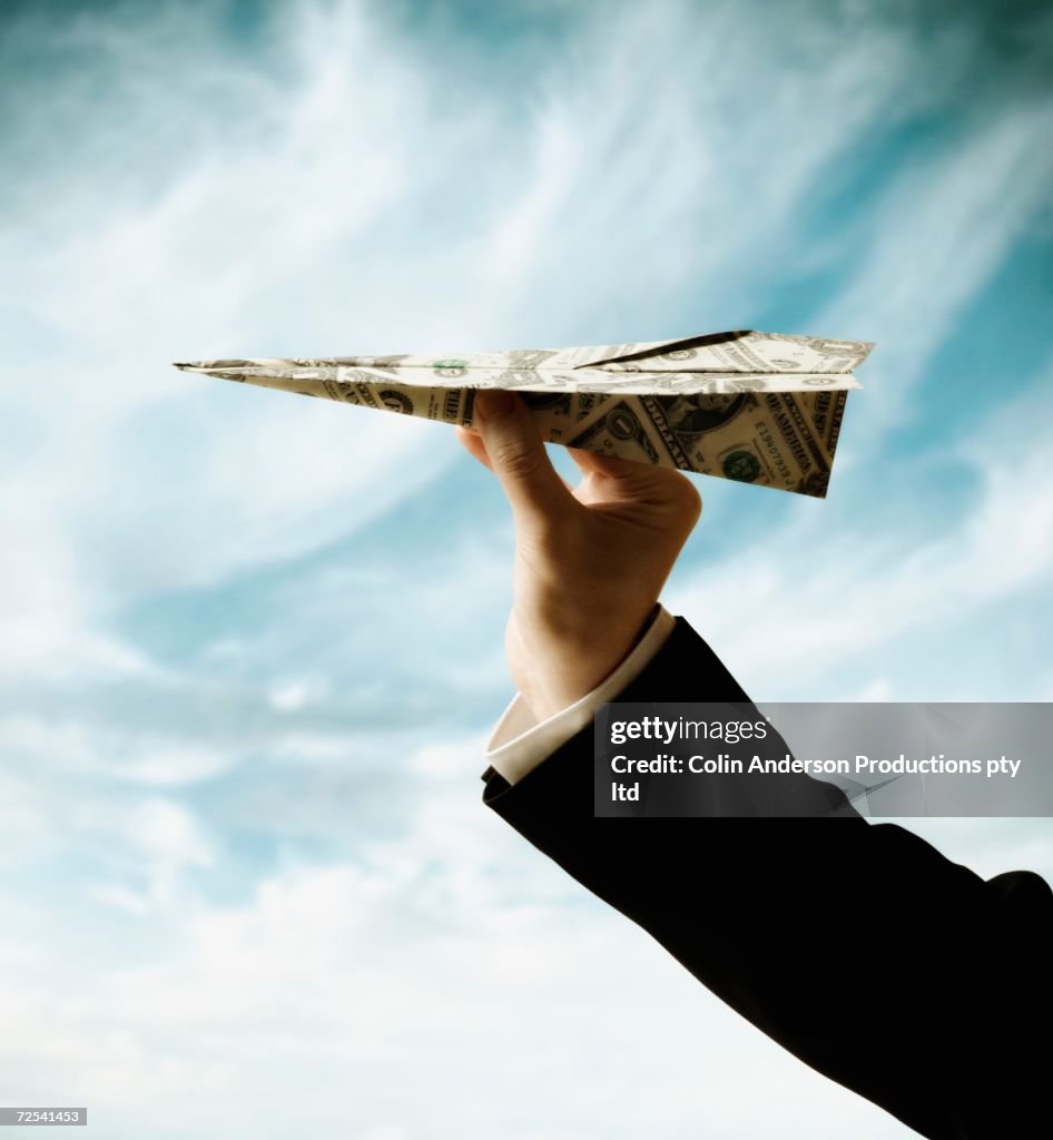 Businessman's hand holding airplane made of US Dollars