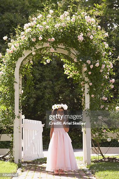 young hispanic girl in fancy dress standing under flowered archway - flower girl stock pictures, royalty-free photos & images