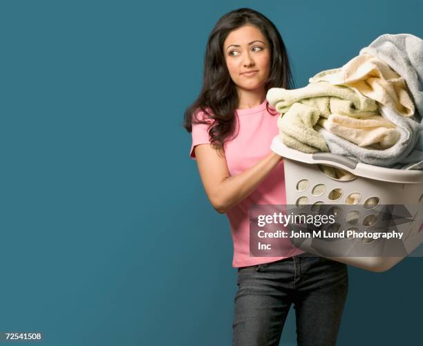 hispanic woman carrying full laundry basket - laundry basket foto e immagini stock