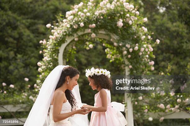 hispanic bride and young girl smiling at each other - mother daughter roses stock-fotos und bilder