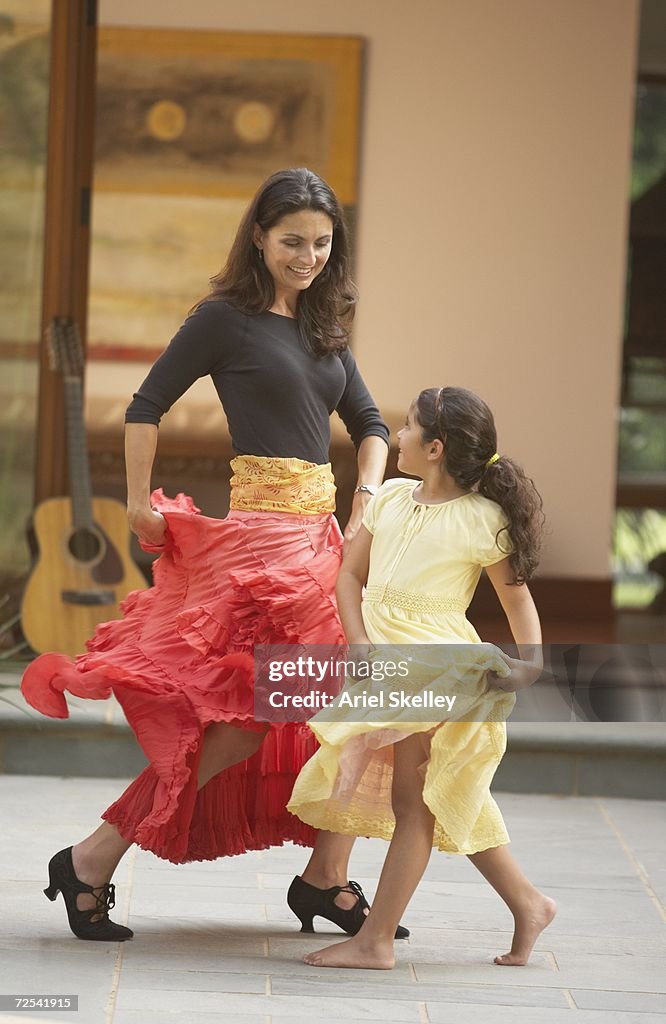 Hispanic mother and young daughter salsa dancing