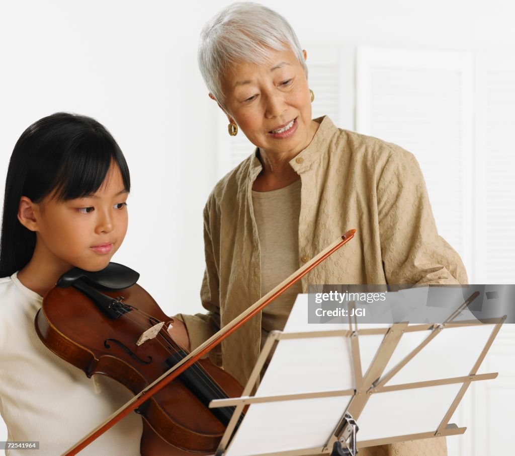 Senior Asian woman teaching young Asian girl violin