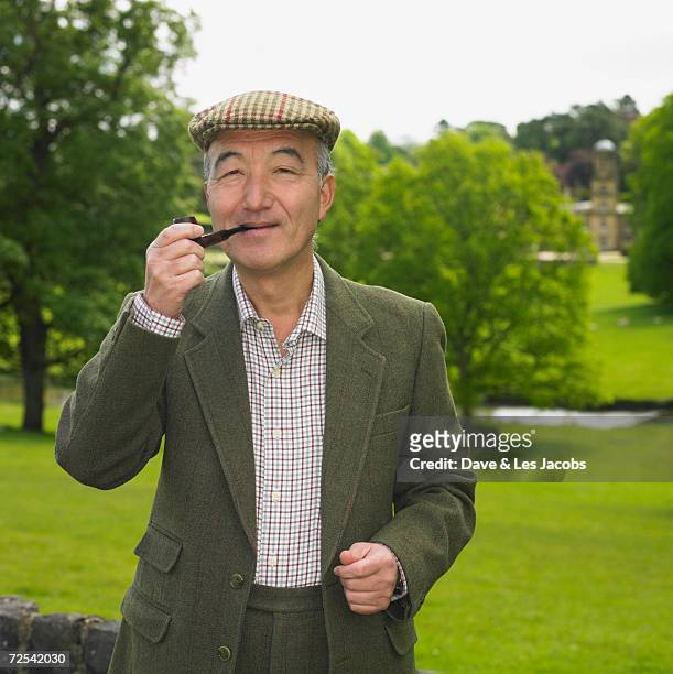 senior asian man smoking pipe outdoors - bauer pfeife stock-fotos und bilder