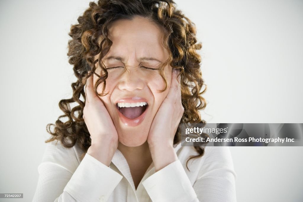Close up of woman yelling and covering ears