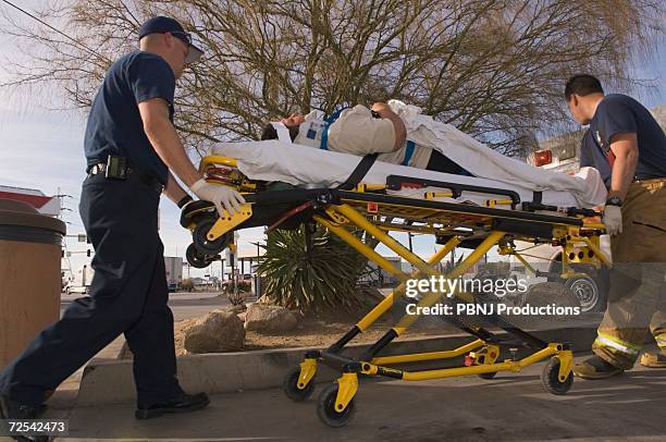 emt workers with accident victim on gurney - disaster victim stock pictures, royalty-free photos & images