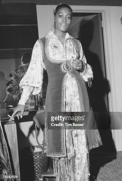 American singer, actress, and television spokesperson Dionne Warwick holds a lit cigarette as she poses for a photograph backstage in her dressing...