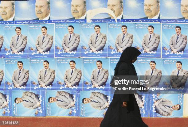 An unidentified woman walks past electoral posters of candidate Ali Ben Flis and Abdelaziz Bouteflika 80km west of Algiers, on April 4, 2004 in...