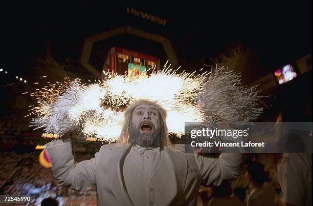 An extreme fan San Richards dressed in a white tuxedo and white face paint cheers as fireworks flare behind him during the Stanley Cup Playoff game...