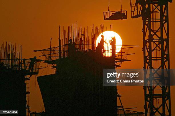 Chinese laborers work at a construction site at sunset March 6, 2005 in Chongqing, China. China's Premier Wen Jiabao announced plans to slow growth...