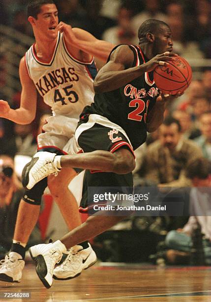 Ruben Patterson of Cincinnati drives around Raef LaFrentz of Kansas in the Great Eight Tournament at the United Center in Chicago, Illinois....