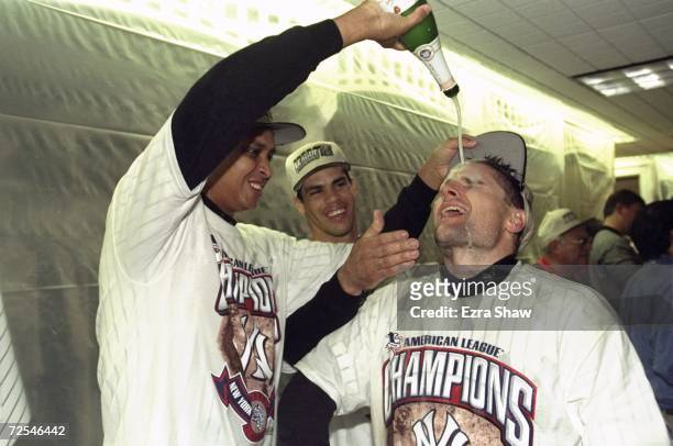 Pitcher Ramiro Mendoza of the New York Yankees pours champagne on infielder Chuck Knoblauch following the American League Championship Series game...