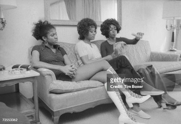 American Motown singing group The Supremes, Jean Terrell, Cindy Birdsong, and Mary Wilson, hold and taunt with food a small dog as they sit on a...